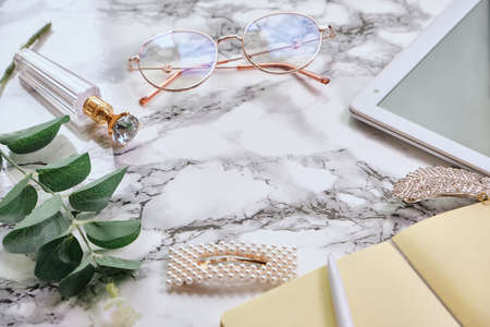 Female White marble office desk table with a lot of things, tablet, notepad, eyeglasses. copy space, flat lay.の写真素材