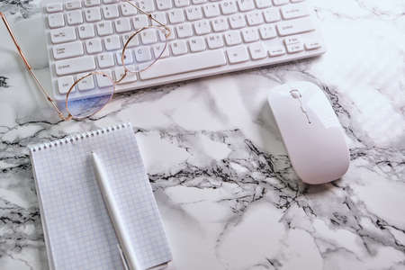Office table with notepad, eyeglasses, keyboard and notepad. View from above with copy spaceの写真素材