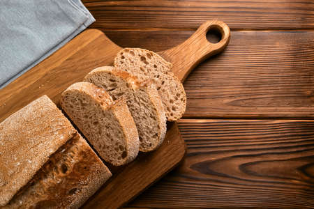 Fresh bread and slices on wooden cutting board