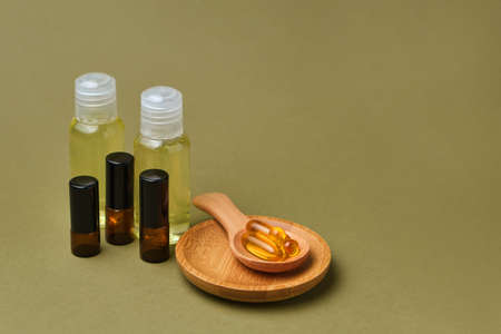 Omega 3 capsules in the wooden spoon on green background, and set of bottles of extract, copy space for your design. Cod liver oil capsules on the table. Healthy life style concept.の写真素材