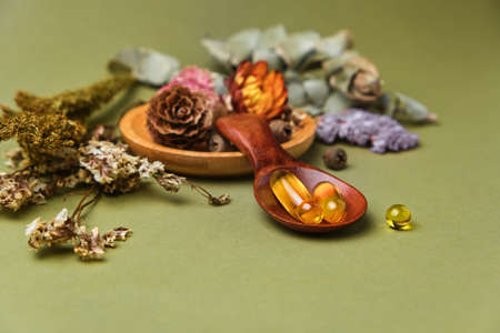 Alternative and herbal medicine, fresh mandarin leaves, capsules with oil and vitamins in wooden...