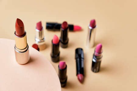 Open lipsticks in different shades of red and pink colors on a beige background.の写真素材