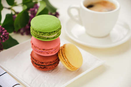 Close up Stack of macaroons and Cup of coffee on a table with lilac flowers
