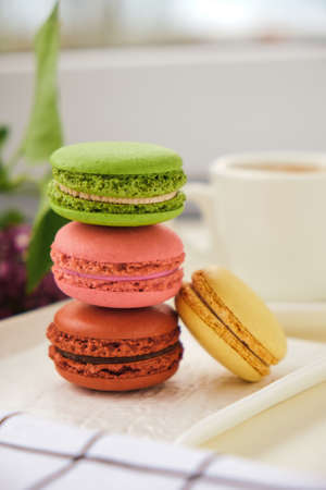 Close up Stack of macaroons and Cup of coffee on a table with lilac flowers