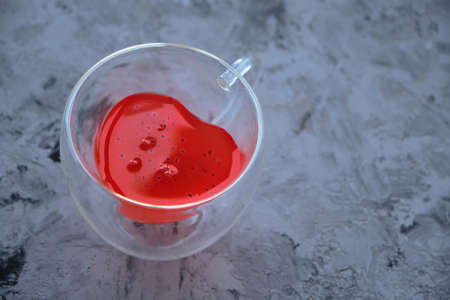 heart-shaped glass mug with red drink on gray background. Flat lay composition for Valentine's Day, birthday, anniversary or wedding.の写真素材