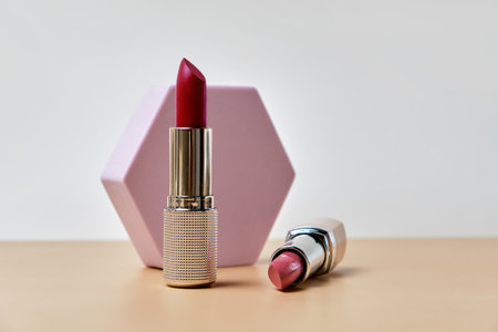 Two open lipsticks, an unbranded presentation of cosmetics on a light beige background with hexagon.の写真素材