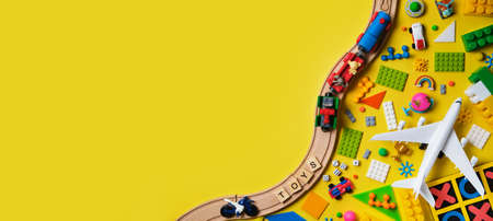 Banner with Set of different children's toys, wooden railroad, train, constructor on a yellow background with copy space for text. Top view, flat lay.の写真素材