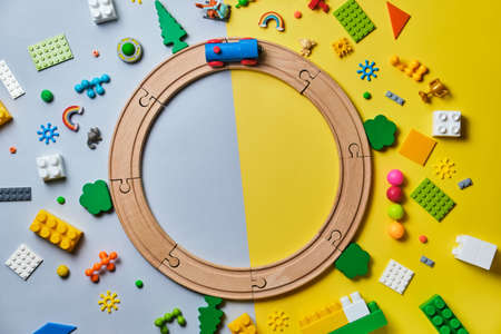 Set of different children's toys, Round made of wooden rails, train, constructor on a yellow and blue background with copy space for text. Top view, flat lay.の写真素材