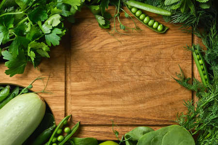 Fresh raw vegetable ingredients for healthy cooking or salad making with rustic wooden cutting board in center, top view, copy space, mock up. Diet or vegetarian food concept, horizontal compositionの写真素材