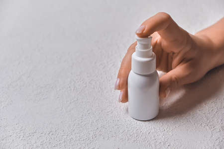 Hand of caucasian young woman holding bottle of body cream over white backgroundの写真素材