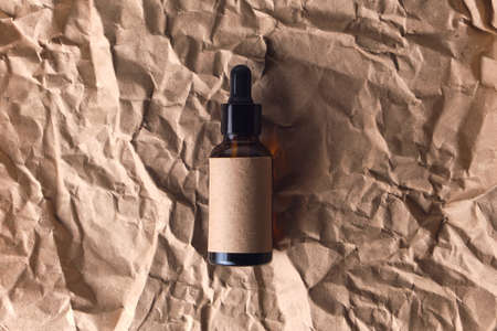 Natural aroma oil in an amber glass brown dropper bottle on crumpled paper. organic beauty product packaging designの写真素材