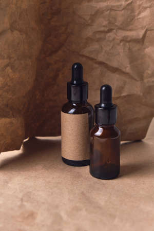 Natural aroma oil in an two amber glass brown dropper bottles on crumpled paper. organic beauty product packaging designの写真素材