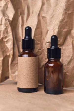 Natural aroma oil in an two amber glass brown dropper bottles on crumpled paper. organic beauty product packaging designの写真素材