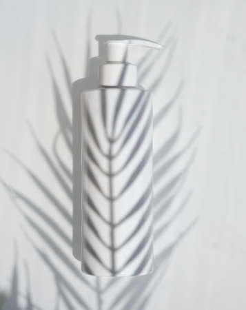Creative minimalistic shot cosmetic packaging plastic mock up with shadow palm leaves. Mock-up for branding and label. natural organic cosmeticの写真素材
