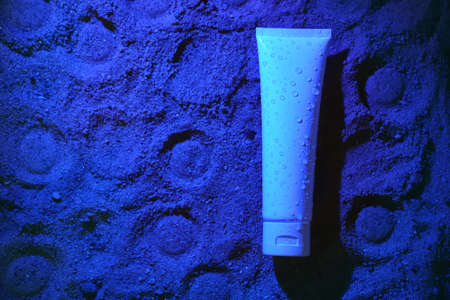 Flat lay. White tube of cream on the blue sand, Lunar surface. Mock up. Packaging design. Sun protection cosmetics. Body lotion or cream with UV protection on beach. Naturalの写真素材