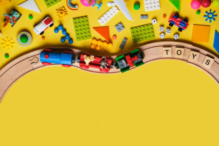Set of different children's toys, wooden railroad, train, constructor on a yellow background with copy space for text. Top view, flat lay.の写真素材