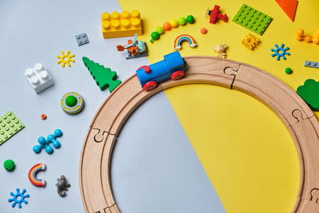 Set of different children's toys, Round made of wooden rails, train, constructor on a yellow and blue background with copy space for text. Top view, flat lay.の写真素材