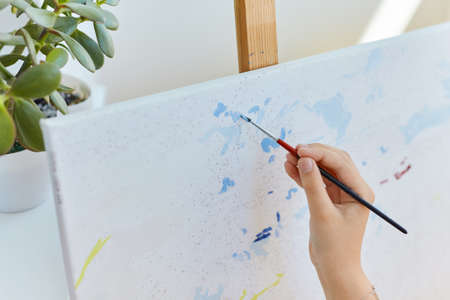 Close up painting by numbers. Kid's hand drawing with paintbrush on numbered canvas. Creative hobby and leisure. Painting for beginners. Art idea. Bright and colorful.の写真素材
