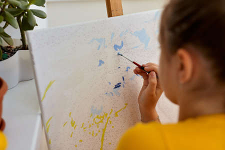 Little girl is painting with gouache. Happy little girl painting in at home. The girl draws a picture by numbers. Close up, selective focus.の写真素材