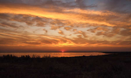 Colorful orange sky and colorful water in lake reflected in the sunsetの写真素材