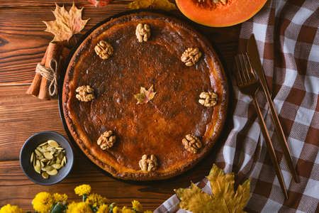 Traditional Pumpkin pie with walnuts and ingredients for cooking on a wooden table. Autumn food in dark style, top viewの写真素材