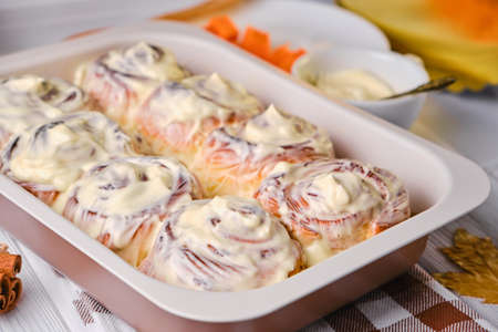Homemade Pumpkin cinnamon rolls with cream cheese in a baking dish, close up, selective focus. Seasonal autumn homemade pastry - cinnabons for breakfast or holidays.の写真素材