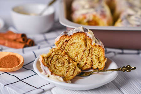Slice of Homemade Pumpkin cinnamon rolls with cream cheese in a baking dish, close up, selective focus. Seasonal autumn homemade pastry - cinnabons for breakfast or holidays.の写真素材