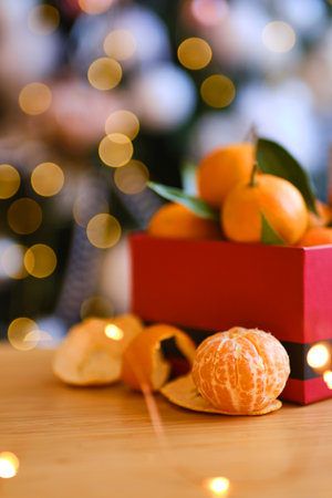 Red gift box of fresh mandarin fruits in a Festive composition on the background of a Christmas tree. Selective focusの写真素材