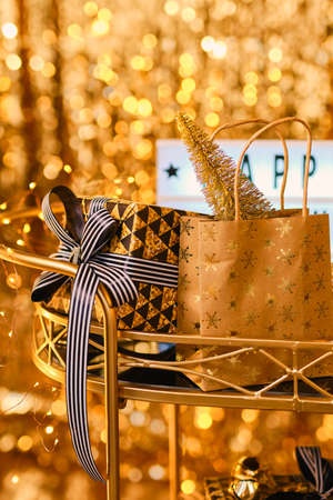 lightbox with the words Happy new Year on a black glass table with Christmas decor and gifts, against the background of a sparkling golden curtain made of sequins, with bokeh.の写真素材