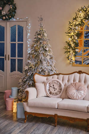 New Year decorated interior. Stylish Christmas interior with an elegant retro sofa. Comfort home. Presents gifts underneath the tree in living room. hoilday celebration photoの写真素材