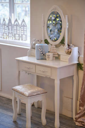 New Year's or Christmas interior decor on white Table Boudoir. Girl's bedroom interior details and makeup, hairstyles with mirrorの写真素材