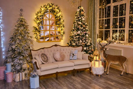 New Year decorated interior. Stylish Christmas interior with an elegant retro sofa. Comfort home. Presents gifts underneath the tree in living room. hoilday celebration photoの写真素材
