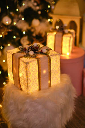 Beautiful Christmas lighting gift boxes on floor near fir tree in roomの写真素材