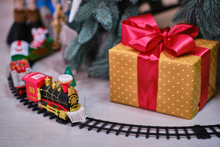 A Toy Train Set on the railroad under the Christmas tree, retro toy. Gifts and New Years surprises for childrenの写真素材