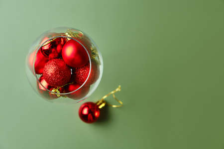 Wine glass filled with red christmas balls on green background. Holiday menu conceptの写真素材