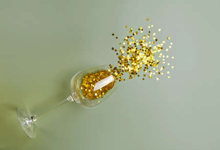 New Year and Christmas party concept. Top view flat lay wine glass with scattered golden star glitter. Copy space. Background minimal style.の写真素材