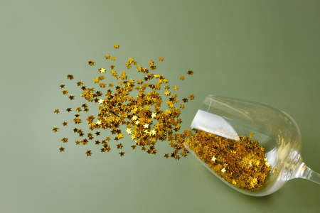 New Year and Christmas party concept. Top view flat lay wine glass with scattered golden star glitter. Copy space. Background minimal style.の写真素材