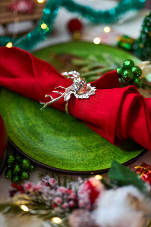 Traditional Christmas table place setting close up. Golden cutlery, linen napkin with deer ring, spruce branches. Holidays background. Flat lay, top view, selective focus.の写真素材