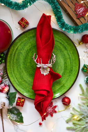 Traditional Christmas table place setting. Golden cutlery, linen napkin with deer ring, spruce branches. Holidays background. Flat lay, top view, selective focus.の写真素材