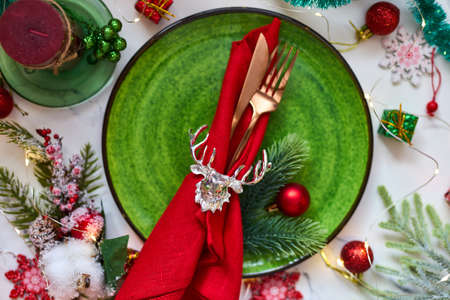 Traditional Christmas table place setting. Golden cutlery, linen napkin with deer ring, spruce branches. Holidays background. Flat lay, top view, selective focus.の写真素材