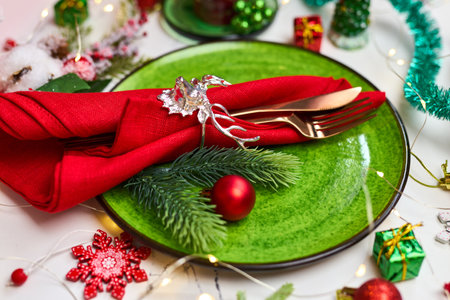 Traditional Christmas table place setting. Golden cutlery, linen napkin with deer ring, spruce branches. Holidays background. Flat lay, top view, selective focus.の写真素材
