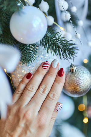 Christmas New Year manicure abstract nail design. Beautiful manicured woman's hand against the background of the christmas treeの写真素材