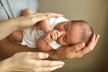 Parents hands holding newborn baby head. Motherhood, fatherhood or parenthood and fathers day concept. modern parenting. Comfort and safety sleep. human insurance. family miracle.の写真素材