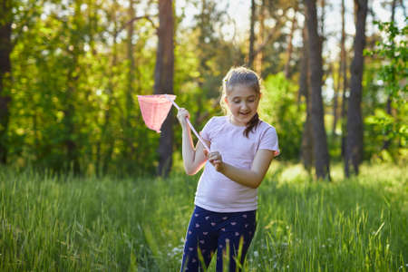 Little girl catches butterflies with a pink juice on a summer dayの写真素材