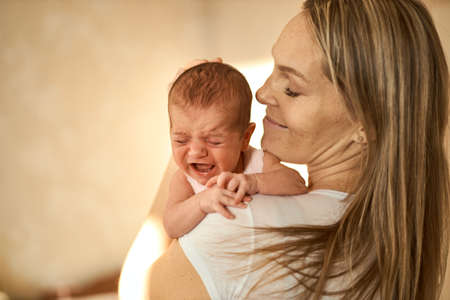 Mother holding her newborn baby in hands. The baby on hands at mum. Loving mother hand holding cute...
