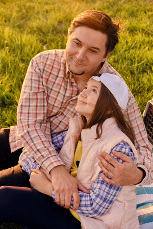 A happy father is having fun with his little daughter in nature, the daughter is hugging her dad and smiling.の写真素材