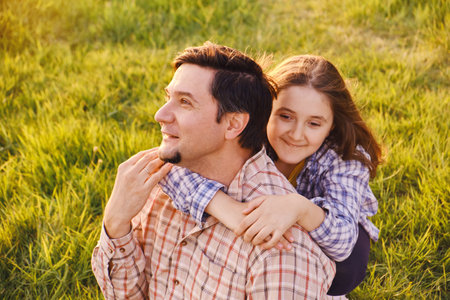 A happy father is having fun with his little daughter in nature, the daughter is hugging her dad and smiling.の写真素材