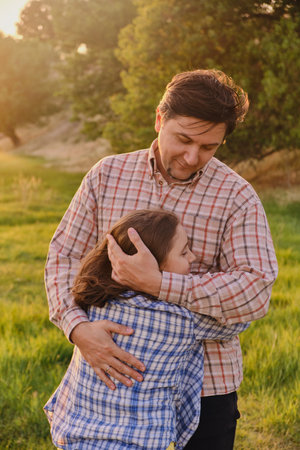 A happy father is having fun with his little daughter in nature, the daughter is hugging her dad and smiling.の写真素材