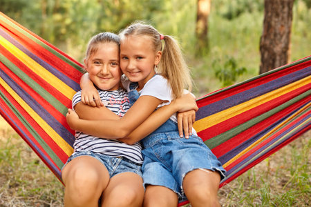 Kids relax in colorful rainbow hammock. Hot day garden fun. Afternoon nap during summer vacation. children relaxing.の写真素材