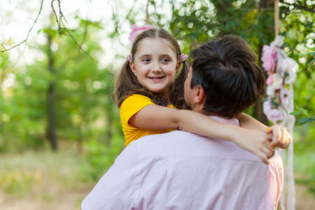 Smiling little girl hugging her father outsideの写真素材